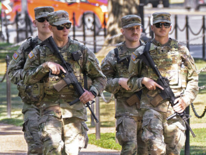 Armed National Guard soldiers walk along Constitution Avenue in Washington during rush hou