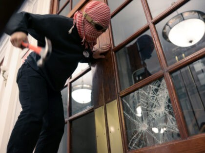 A demonstrator breaks the windows of the front door of the building in order to secure a c