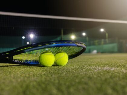 play tennis in dark with artificial lighting. racket and balls on outdoor court with copy