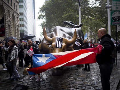 Protesters hold a Puerto Rican flag in front of the Charging Bull statue during a demonstr