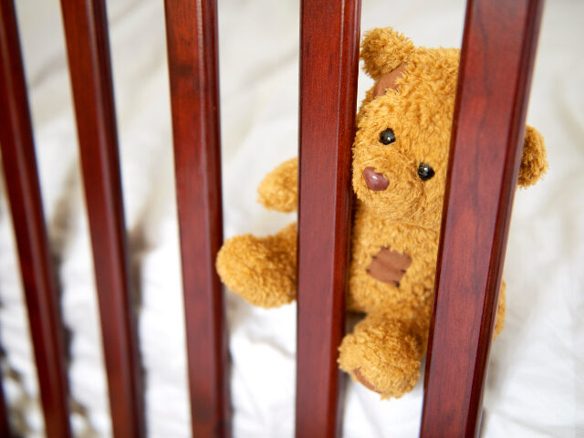 Teddy bear in empty crib