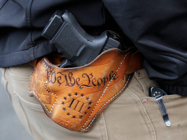 An attendee at a gun-rights rally open carries his gun in a holster that reads "We th