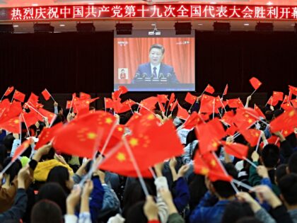 College students wave national flags as they watch the opening of the 19th Communist Party