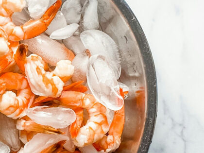 a metal bowl filled with shrimp on top of a table