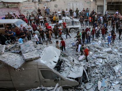 Palestinians are seen among the rubble of destroyed buildings after an Israeli airstrike i