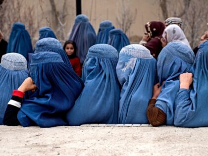 Afghan burqa-clad women wait in a queue to receive free iftar meal during the Islamic holy