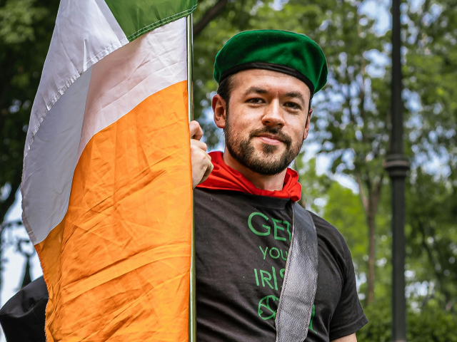 A man in a kilt holding an Irish flag
