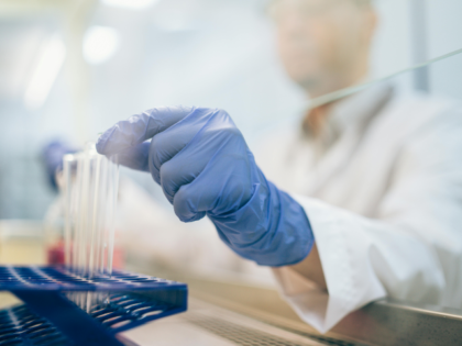 A Person Wearing Medical Glove Putting the Test Tube on a Rack