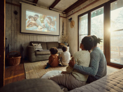 Rear view of relaxed African American family watching a movie in the living room.