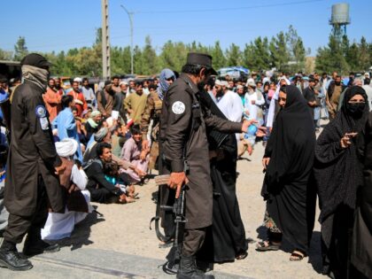 Taliban personnel stand guard as Afghans deported from Iran, await food aid distributed in