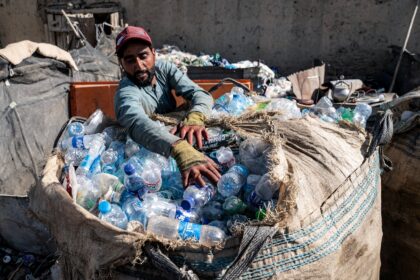 An Afghan worker loads plastic bottles into a sack at a recycling yard in Kabul
