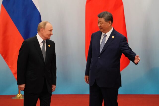 Chinese President Xi Jinping shows the way to Russian President Vladimir Putin after the p
