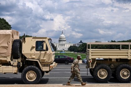 A member of the US National Guard walks past military vehicles on the National Mall in Was