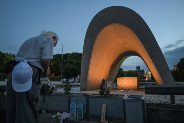 Visitors pray for atomic bomb victims in front of the memorial cenotaph in Hiroshima