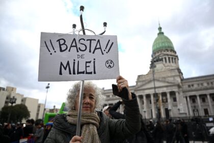 A woman holds a sign that reads in "Enough of Milei," outside of National Congre