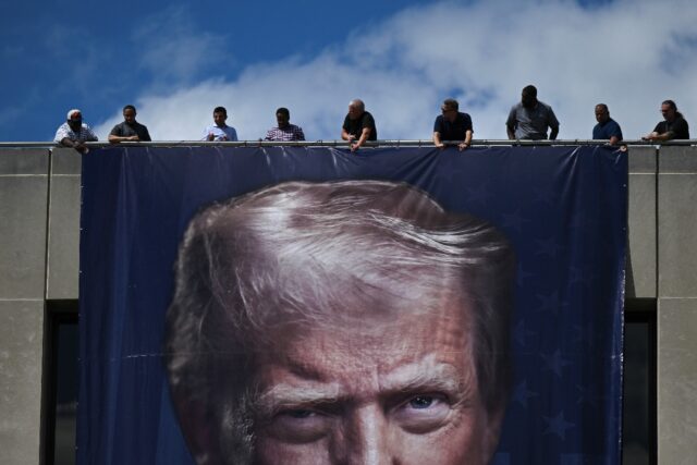 Workers hang a large photo of US President Donald Trump on the facade of the Department of