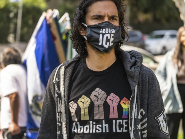 Activist Adam de Monet wears an "Abolish ICE" T-shirt and face mask as he partic