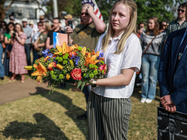 A mourner holds flowers during a wreath laying ceremony outside the US Embassy in Pretoria