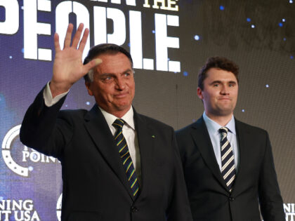 Far-right former Brazilian President Jair Bolsonaro waves as he stands with Charlie Kirk,