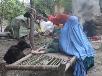 An Afghan women and children sit in a makeshift camp in the aftermath of an earthquake, in