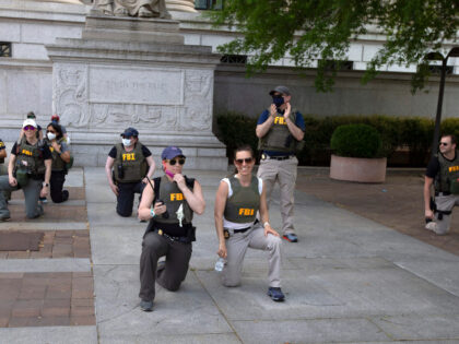 FILE - Federal Bureau of Investigation (FBI) officers take a knee with demonstrators, as t