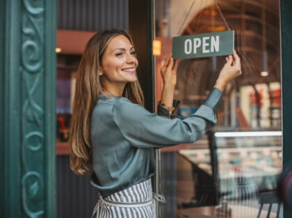 Young woman owner of ice cream shop in town. She is opening her store and waiting for cost