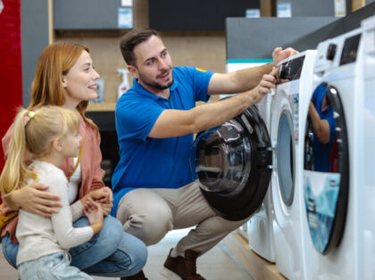 A friendly salesman shows a family the features of a washing machine in an appliance store