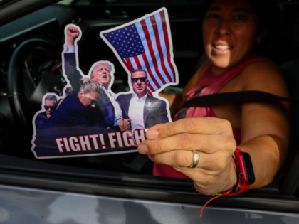 PALM BEACH, FLORIDA - DECEMBER 14: A person gives away stickers of U.S. President-elect Do