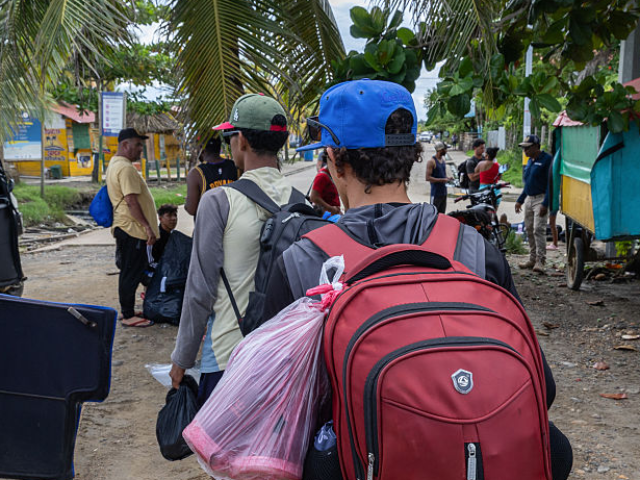 Migrants returning from the US border carry belongings after arriving by boat in Necocli,