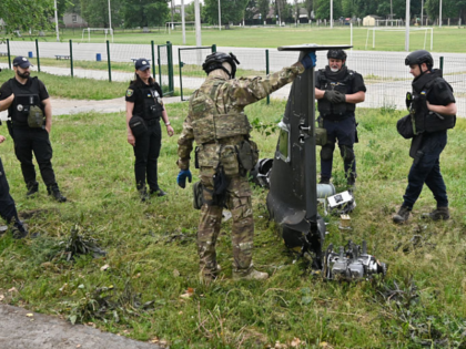 Ukrainian explosives experts and police officers examine parts of a Shahed 136 military dr