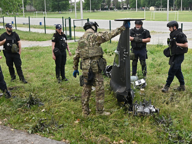 Ukrainian explosives experts and police officers examine parts of a Shahed 136 military dr