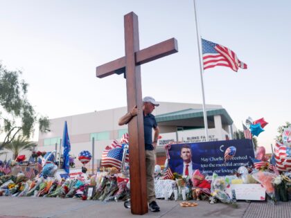 PHOENIX, ARIZONA - SEPTEMBER 12: A man stands with a cross at a memorial for Charlie Kirk