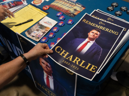 Attendees pick up posters of Turning Point USA founder Charlie Kirk during a vigil at Dese
