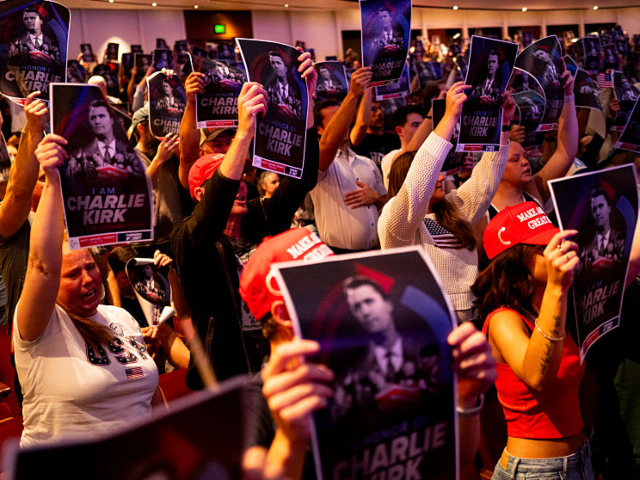 MINNEAPOLIS, MINNESOTA - SEPTEMBER 22: Attendees hold up posters of Charlie Kirk during th