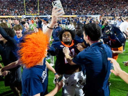 CHARLOTTESVILLE, VIRGINIA - SEPTEMBER 26: Fans rush the field and celebrate with Keke Adam