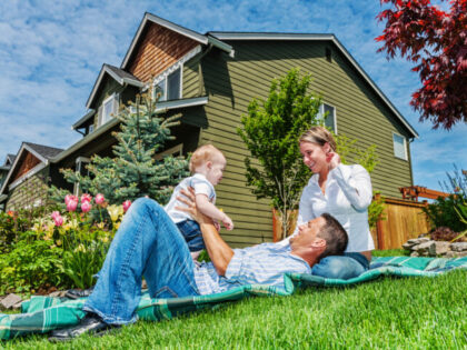 Photo of a happy family in front of their home, enjoying a sunny day in the yard on a blan