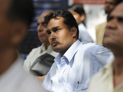 Indian onlookers watch share prices on the stock exchange ticker outside the Bombay Stock