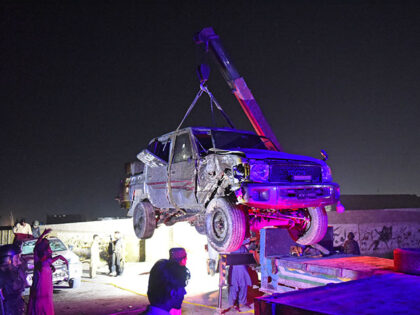 Security personnel inspect a damaged vehicle at the site of an explosion after a suicide b