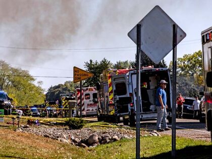 Neighbors and other community members look on as emergency services respond to a shooting