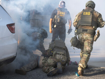A demonstrator is taken into custody by federal law enforcement agents as tear gas fills t