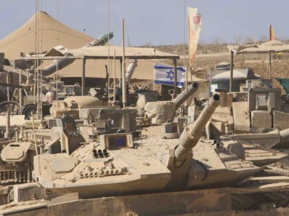 Israeli soldiers work on their tanks at a staging area on the border with Gaza Strip, in s