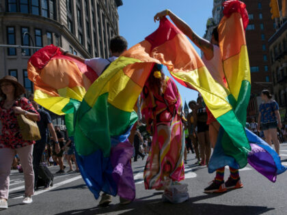 In this June 30, 2019, file photo, parade-goers pose for photographs with rainbow flags du