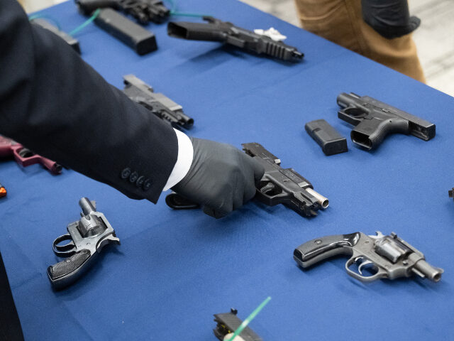 A member of law enforcement handles firearms that were recovered during the arrests of an