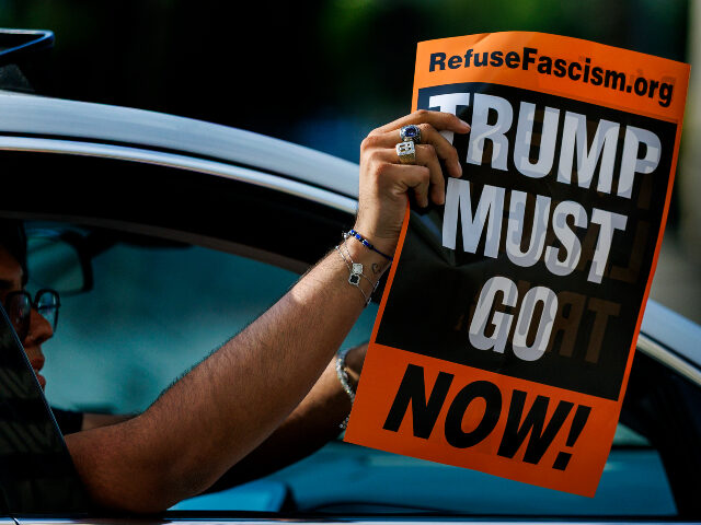 Refuse fascism poster A passenger in a moving vehicle waves an anti-Trump poster while driving by a "Good T