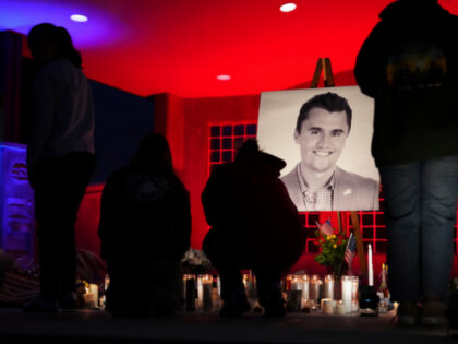 People place lit candles below a photo of Charlie Kirk, the CEO and co-founder of Turning