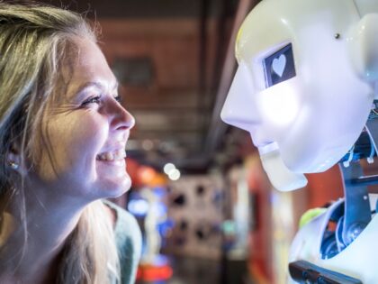 Happy technician looking at human robot with heart shape in eye