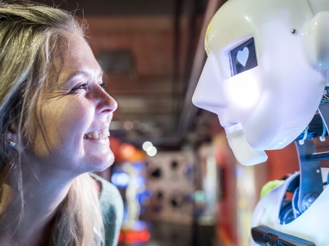 Happy technician looking at human robot with heart shape in eye