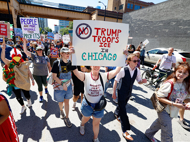 Protesters hold signs as they march during a "Workers over billionaires" rally on Labor Da
