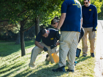 Law enforcement officials, including members of an FBI forensics team, investigate near th