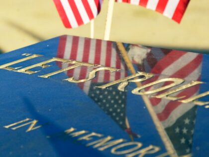American flags are reflected in a marker inscribed with the words "Let's Roll...